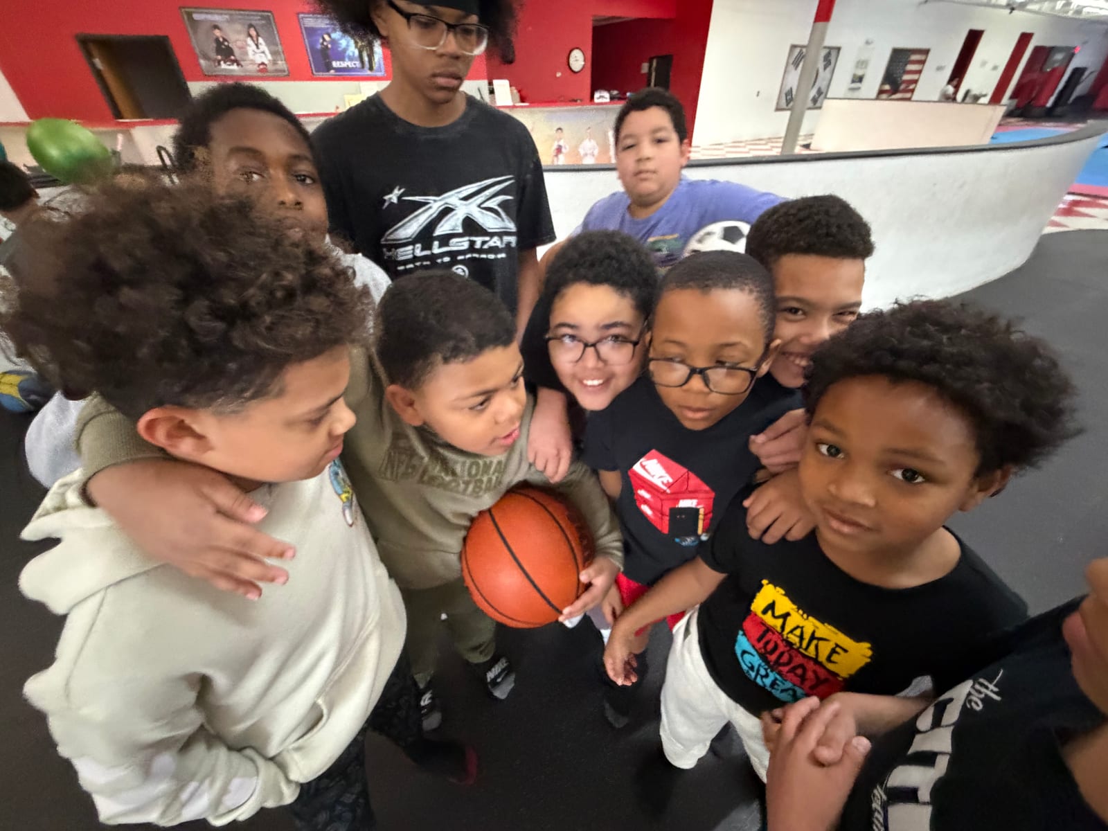 Kids huddled together smiling with a basketball